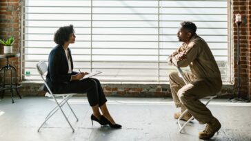 Photo of Man and Woman Sitting Beside Window