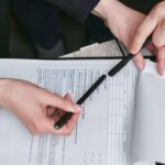Person Holding Black Pen Reviewing a Document