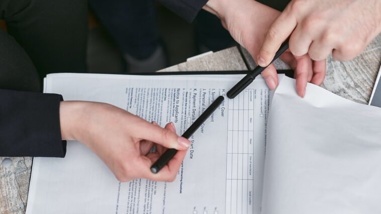 Person Holding Black Pen Reviewing a Document