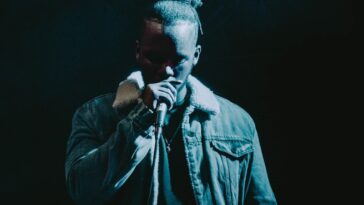 Man Wearing Denim Jacket Singing on Stage
